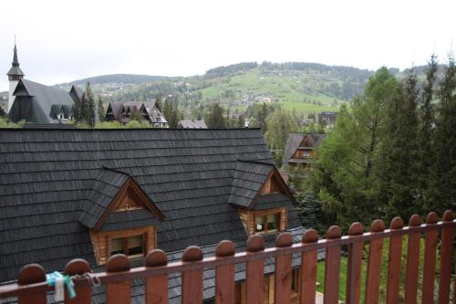 ein Haus mit einem schwarzen Dach und einem Holzzaun in der Unterkunft Willa Senator in Zakopane