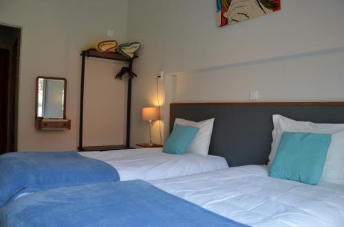 a bedroom with two beds with blue and white sheets at Hotel Girassol in Porto