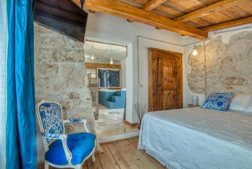 a bedroom with a bed and a blue chair at Trulli Terra Magica in Putignano
