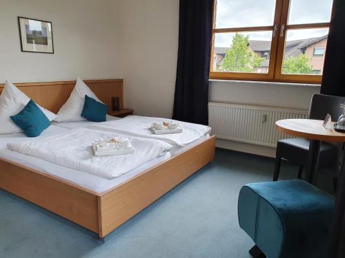 a bedroom with a bed and a table and a window at Olympia Hotel & Restaurant in Inden