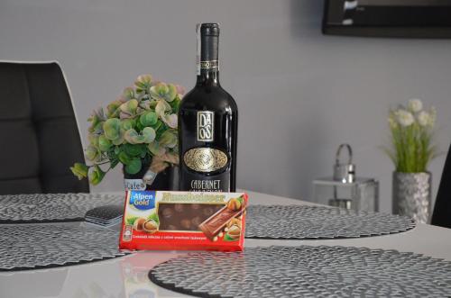 a bottle of wine and a box of chocolates on a table at Apartament DeLuxe 1 in Oświęcim