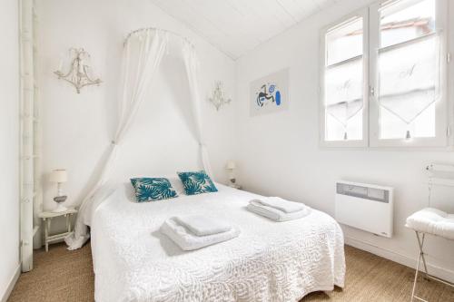 Un dormitorio blanco con una cama con toallas. en Appartement Liseron, en Saint-Martin-de-Ré