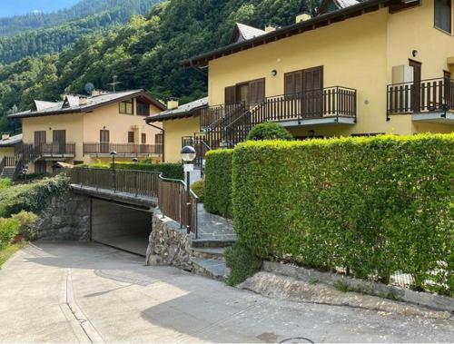 a house with a hedge in front of a building at Appartamento con Giardino e Box in Valmalenco in Torre di Santa Maria