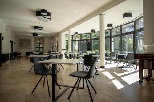 un restaurante con mesas, sillas y ventanas grandes en Hotel Kasteel Solhof en Aartselaar