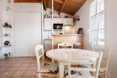 une petite cuisine avec une table et des chaises blanches dans l'établissement Appartement Silène, à Saint-Martin-de-Ré