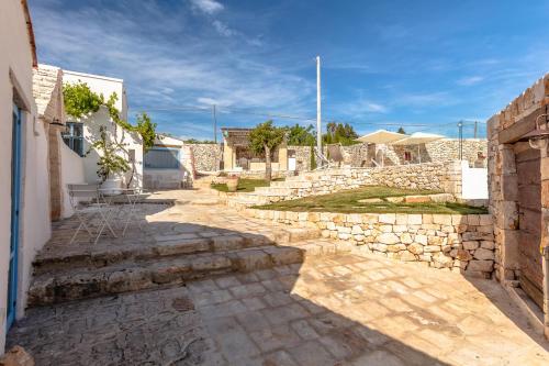 a stone walkway in a village with a stone wall at Trulli Terra Magica in Putignano