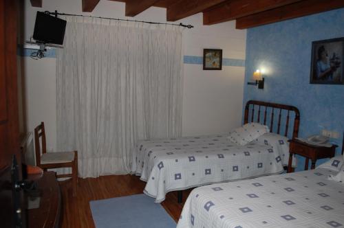 a hotel room with two beds and a television at HOTEL RURAL EL DENARIO in Garray