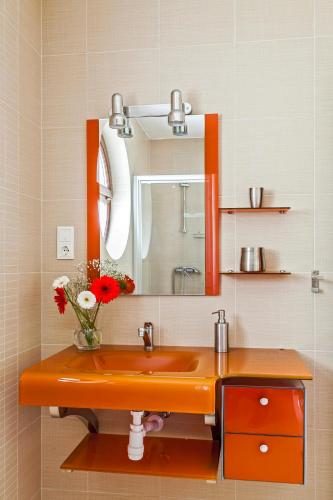 a bathroom with an orange sink and a mirror at Panoramic Art Apartment with jacuzzi in Balatonlelle