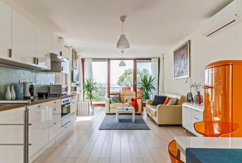 une cuisine avec des placards blancs et un salon dans l'établissement Panoramic Art Apartment with jacuzzi, à Balatonlelle