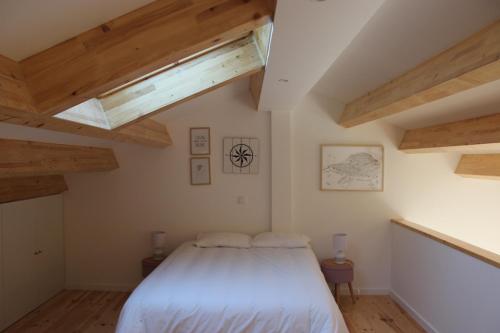 1 dormitorio con techo de madera y cama blanca en Casa da Ponte Branca en Ancião