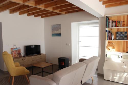 a living room with a white couch and a tv at Casa da Ponte Branca in Ancião