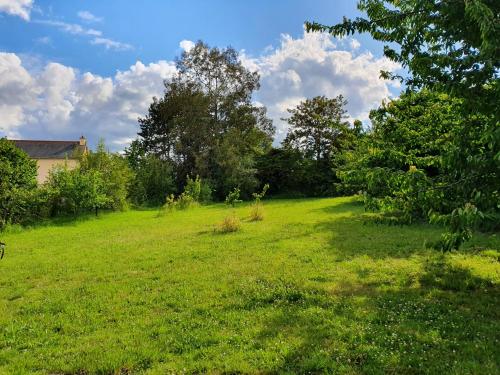 a field of green grass with trees and a house at Villa Bretonne in Langueux