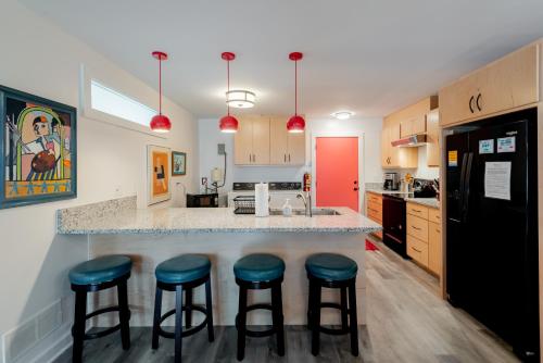 a kitchen with blue stools at a kitchen counter at Folly Vacation Perfect Purple Palace Apt A in Folly Beach