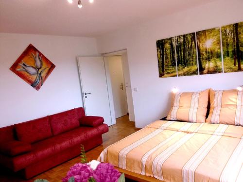 um quarto com uma cama e um sofá vermelho em Helles Apartment mit Balkon am Großen Garten nahe Stadtzentrum em Dresden