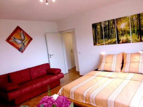 ein Schlafzimmer mit einem Bett und einer roten Couch in der Unterkunft Helles Apartment mit Balkon am Großen Garten nahe Stadtzentrum in Dresden