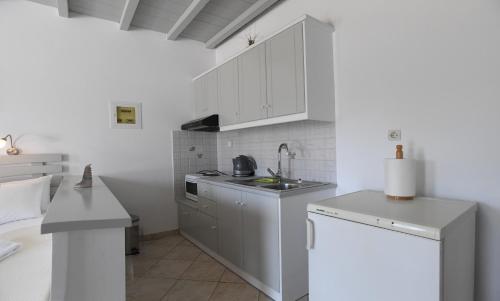 a kitchen with white cabinets and a sink at Nostos Beachfront Apartments & Studios in Agios Ioannis Tinos