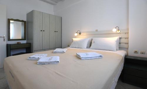 a bedroom with a large bed with towels on it at Nostos Beachfront Apartments & Studios in Agios Ioannis Tinos
