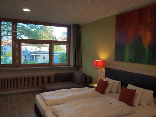 Hotel „Zur Linde“ في Ehingen: غرفة نوم بسرير واريكة ونافذة