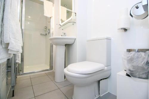a white bathroom with a toilet and a shower at Kelvingrove Hotel - Sauchiehall St in Glasgow