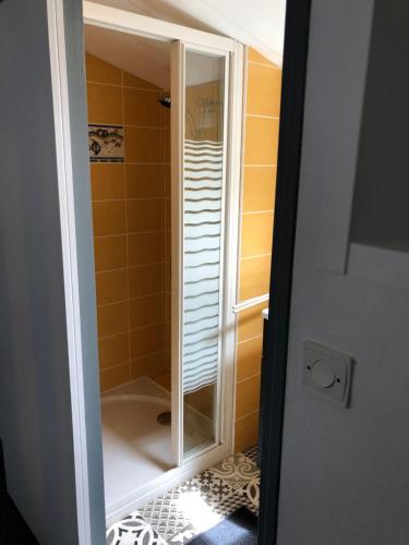 een douche met een glazen deur in de badkamer bij Petite maison tout confort in Esnandes