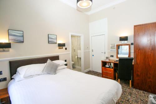 a bedroom with a bed and a desk and a chair at Kelvingrove Hotel - Sauchiehall St in Glasgow