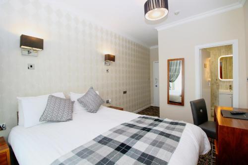 a bedroom with a large white bed and a desk at Kelvingrove Hotel - Sauchiehall St in Glasgow