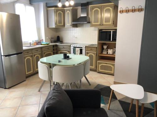 uma cozinha com uma mesa e cadeiras e um frigorífico em Petite maison tout confort em Esnandes