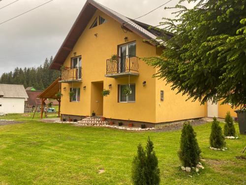 a yellow house with balconies on a green yard at Casa Natalia Raisa Arieșeni in Arieşeni