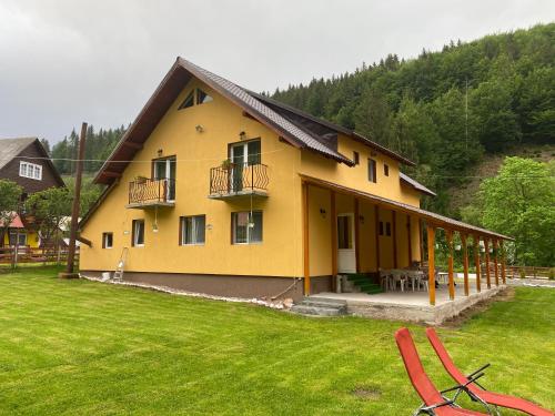 a yellow house with a patio and a grass yard at Casa Natalia Raisa Arieșeni in Arieşeni