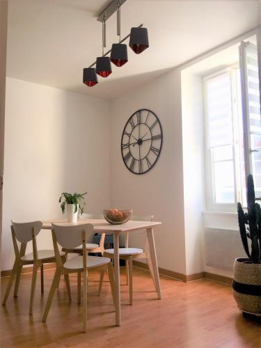 une salle à manger avec une table et une horloge au mur dans l'établissement Grande Plage La Garçonnière du Palais 3 étoiles de charme, à Les Sables-dʼOlonne