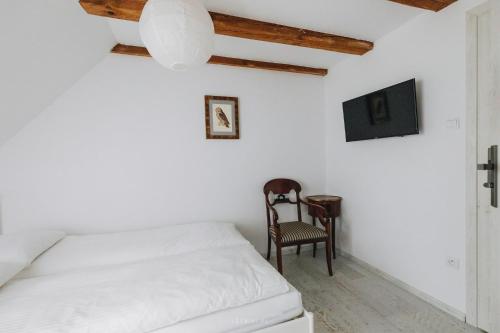 a white bedroom with a bed and a chair at Leśniki in Babimost