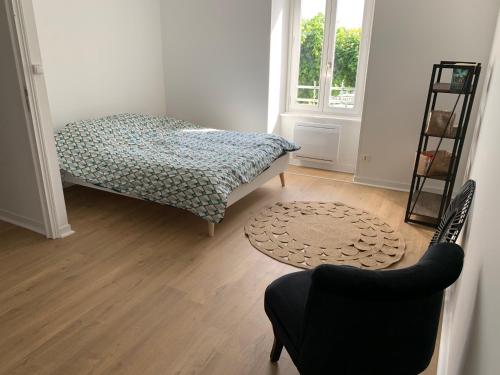 1 dormitorio con 1 cama, 1 silla y 1 ventana en Appartement au cœur d’Auray au 1er étage, en Auray