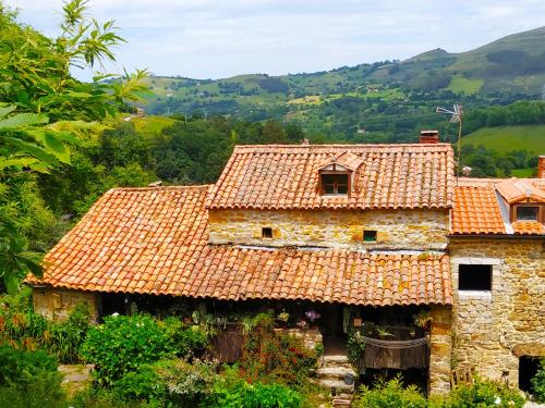 an old stone house with a red tile roof at Apartamento en Plena Naturaleza in La Cavada