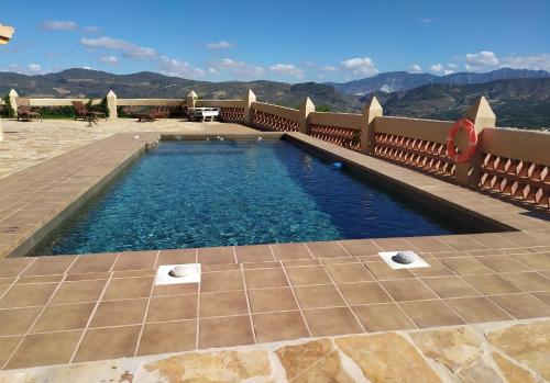 a swimming pool on a patio with mountains in the background at Cortijo Don Enrique in Restábal