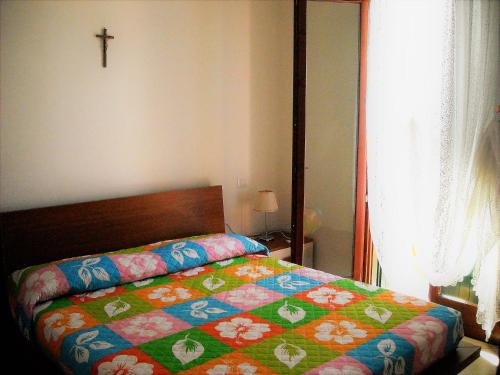 a bedroom with a bed with a colorful quilt on it at RESORT VILLAGE AQUA MARINA FAMILY - Daily Rooms Tidying - CocktailsBar- Pet Friendly - with Hypermarket - Delivery Restaurant-Pizzeria - Room Breakfast with supplement - Ultra Fast Wi-Fi - Play Area for children - Olympic Swimming Pool - Parking in Caorle