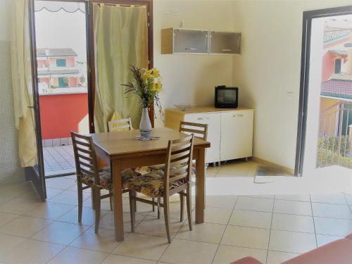 a dining room table with chairs and a vase with flowers on it at RESORT VILLAGE AQUA MARINA FAMILY - Daily Rooms Tidying - CocktailsBar- Pet Friendly - with Hypermarket - Delivery Restaurant-Pizzeria - Room Breakfast with supplement - Ultra Fast Wi-Fi - Play Area for children - Olympic Swimming Pool - Parking in Caorle