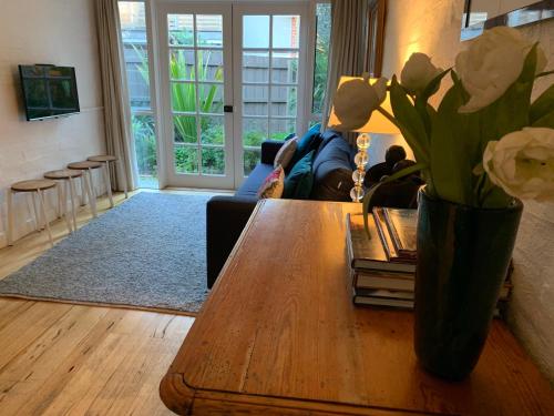 Garden Cottage St Kilda في ملبورن: غرفة معيشة مع طاولة عليها زهور