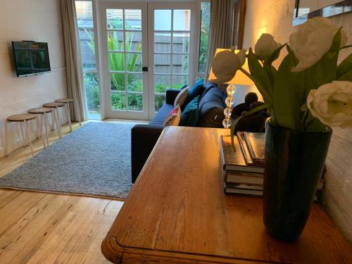 a living room with a table with flowers on it at Garden Cottage St Kilda in Melbourne