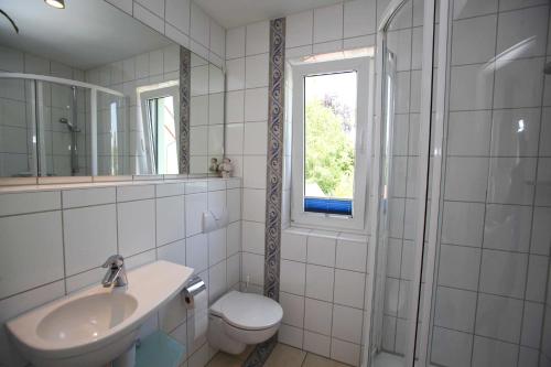 a bathroom with a sink and a toilet and a window at Fewo Kaiser Am Lindenpark - Free Wifi in Kühlungsborn