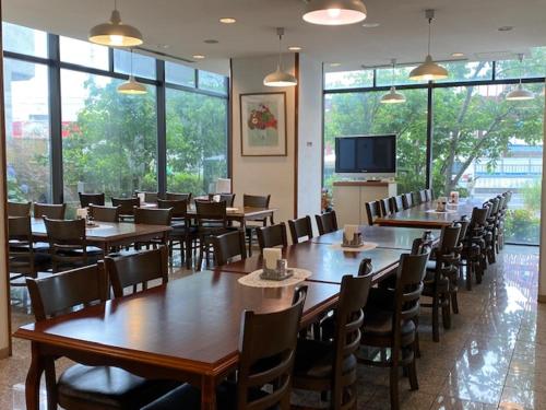 a restaurant with tables and chairs and a television at Hotel New Yutaka in Izumi-Sano