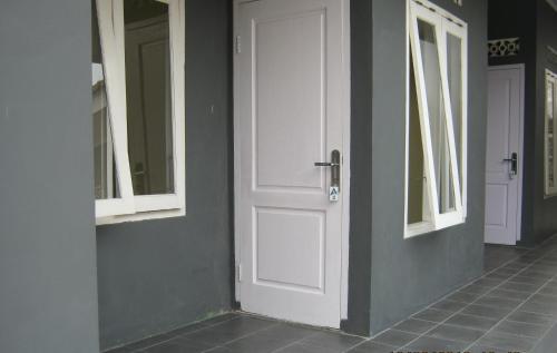 a white door on a wall with two windows at Aqilakost Gadog Puncak Bogor in Bogor