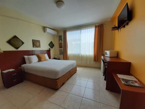 Habitación de hotel con cama, escritorio y TV. en Hotel Air Suites, en Guayaquil
