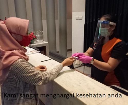 a woman in a mirror with a person wearing a mask at Cabin Hotel in Jakarta