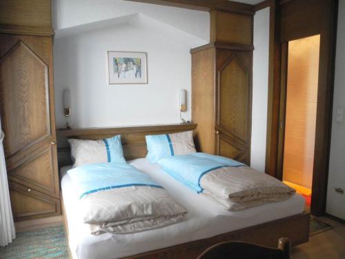 a bed with blue and white pillows on it at Haus Herzog in Matrei in Osttirol