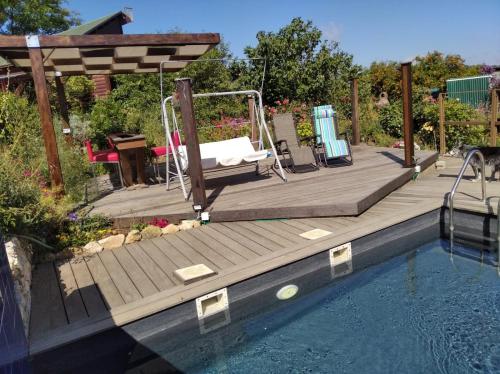 una terraza de madera con un columpio junto a una piscina en Hahar Aatzil, en H̱azon