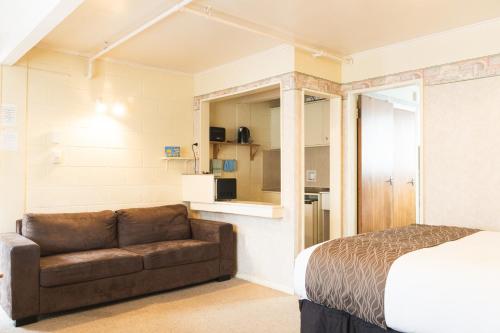 - un salon avec un canapé et un lit dans l'établissement Mayfair Court Motel, à Tokoroa