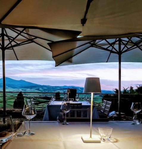 a table with wine glasses and a lamp on it at Relais Il Chiostro Di Pienza in Pienza