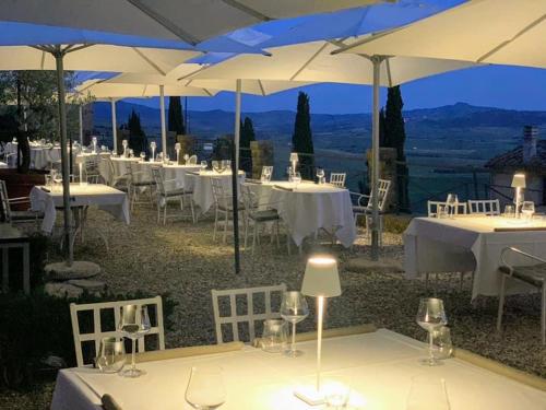 
a dining area with tables, chairs and umbrellas at Relais Il Chiostro Di Pienza in Pienza

