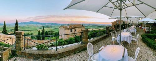 a restaurant with tables and umbrellas and a view at Relais Il Chiostro Di Pienza in Pienza