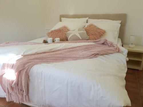 a bed with pink and white sheets and pillows at Apartments Habek in Vrboska